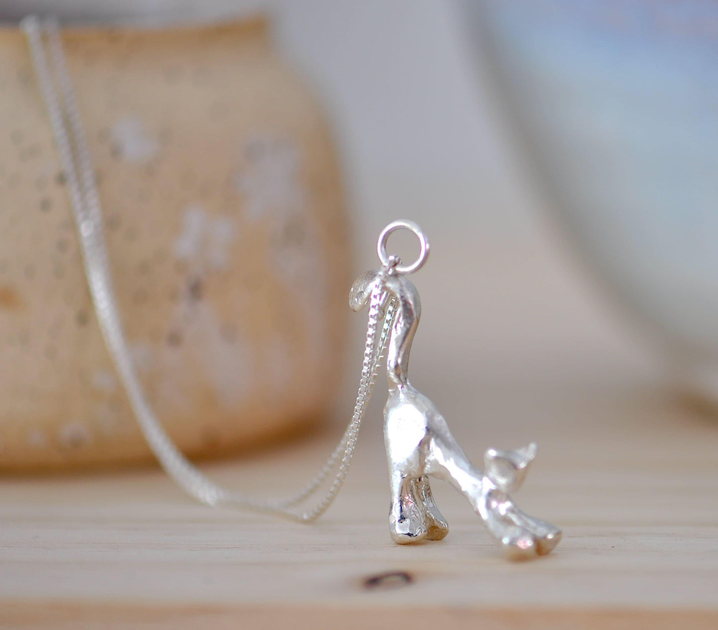 a silver necklace with a small dog on it