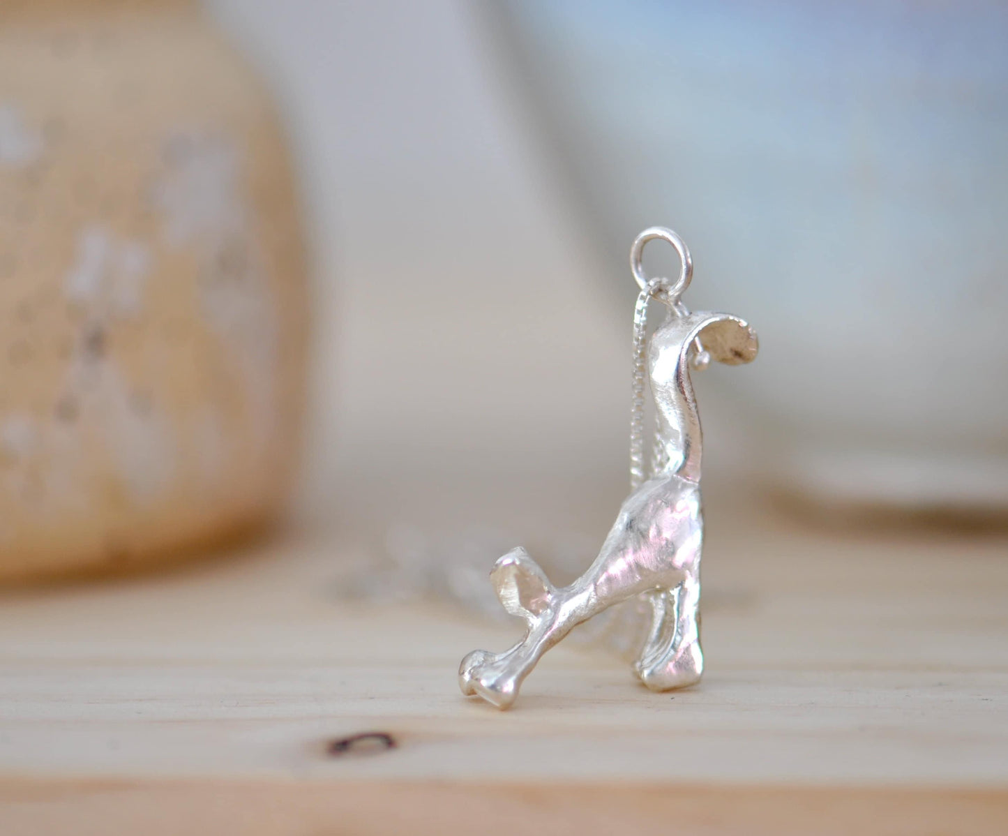 a silver dog charm sitting on top of a wooden table