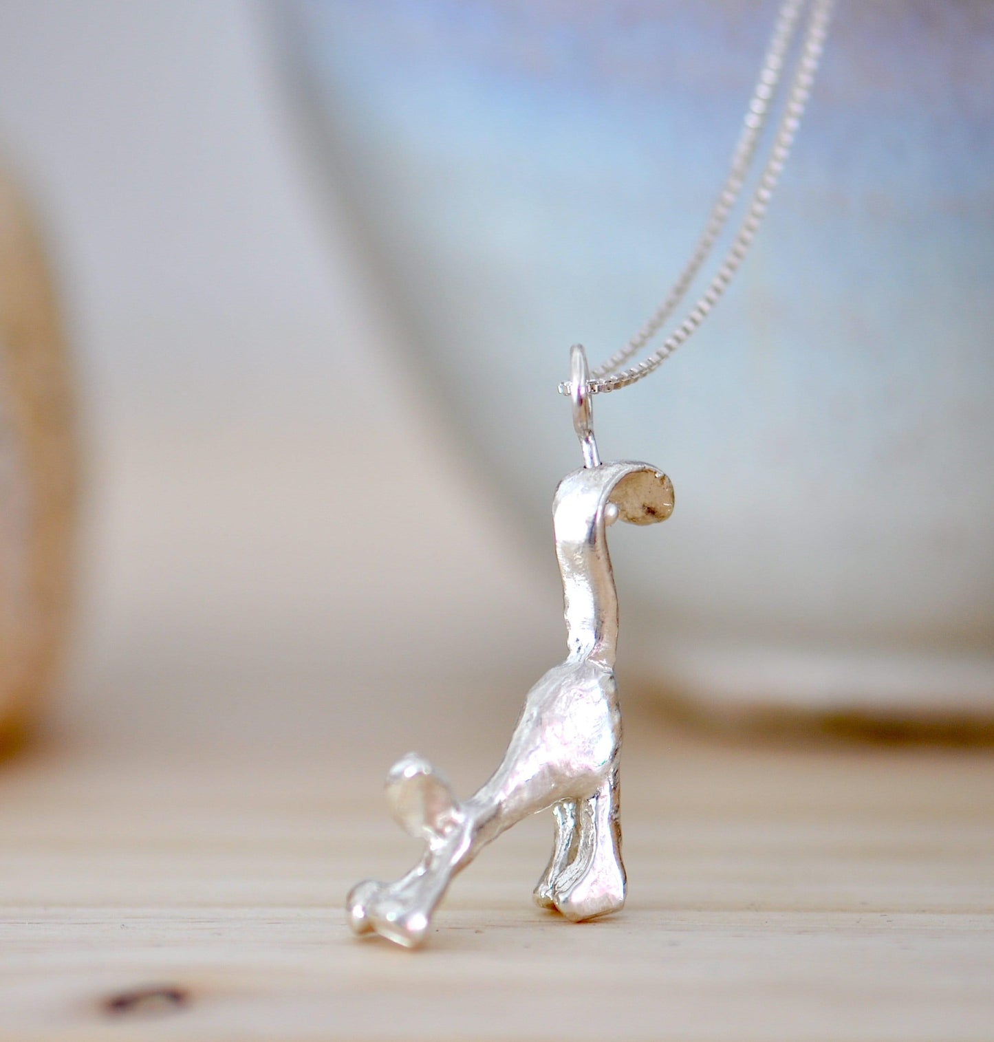 a small silver dog necklace on a table