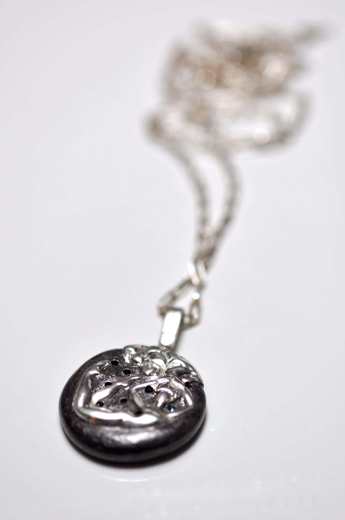 a silver necklace with a face on it