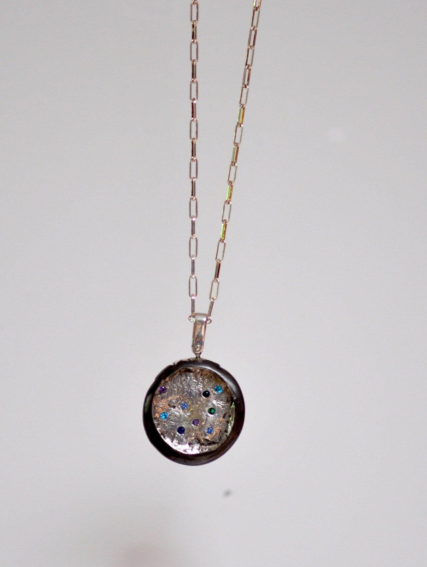 a necklace with a glass disc hanging from a chain