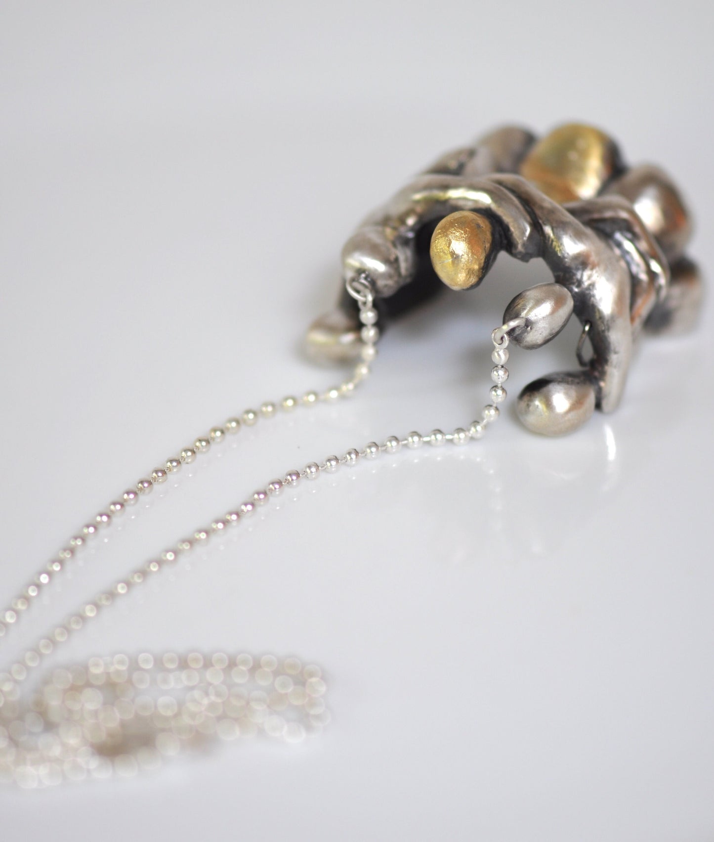 a silver necklace with pearls on a white surface