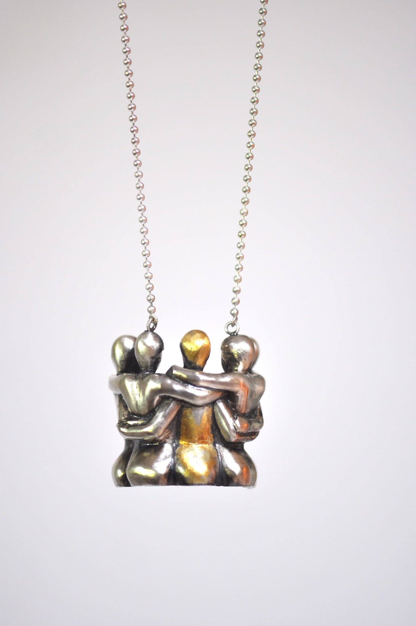 a silver necklace with two people holding each other