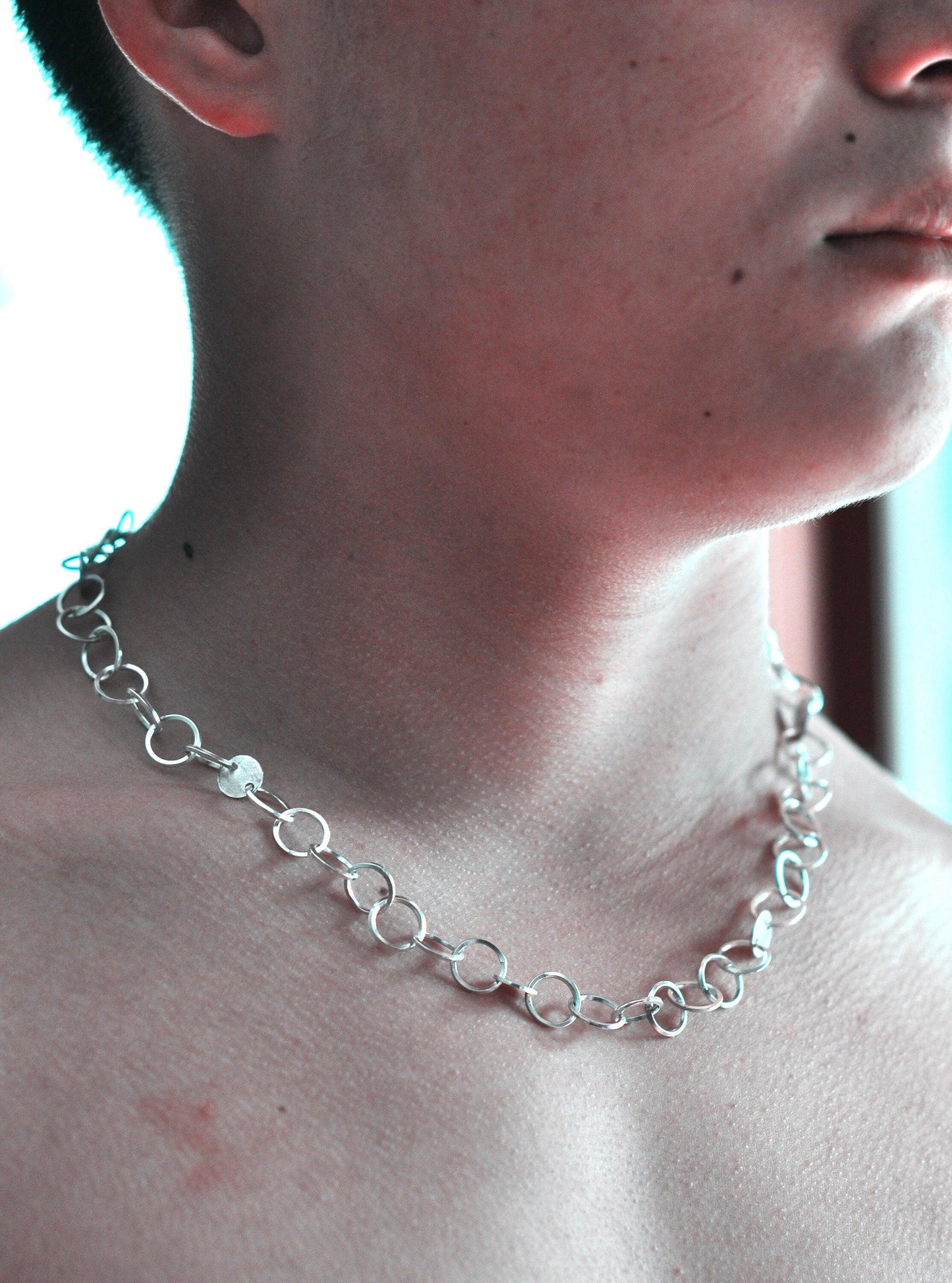 a shirtless man wearing a silver chain necklace