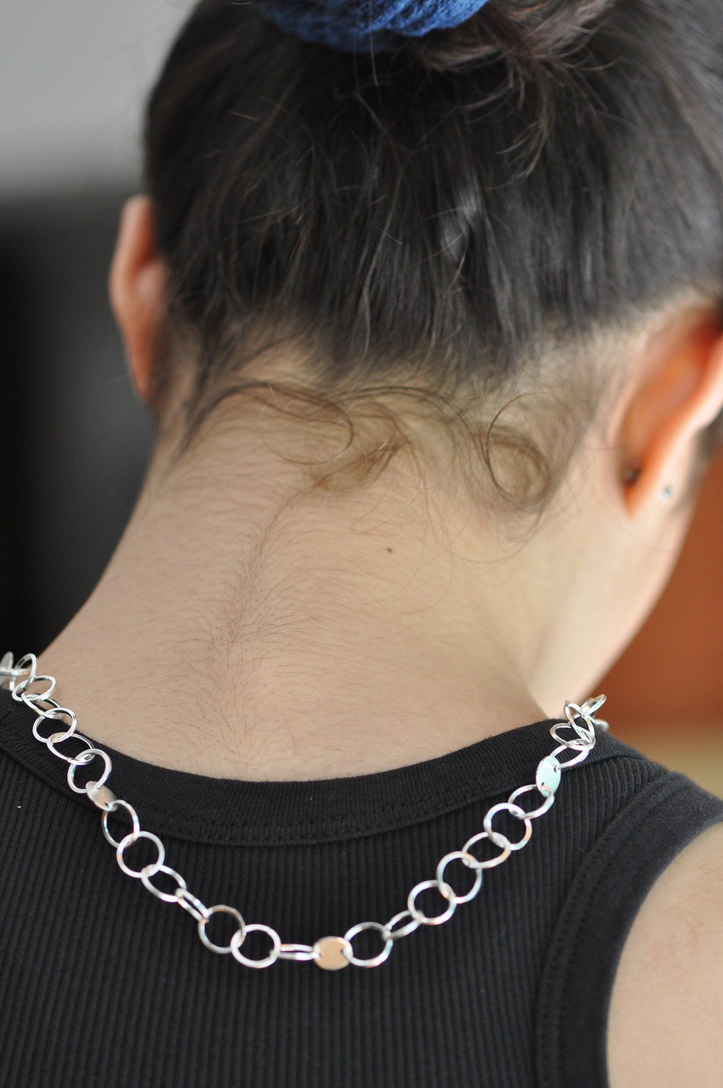 the back of a woman's neck wearing a chain necklace