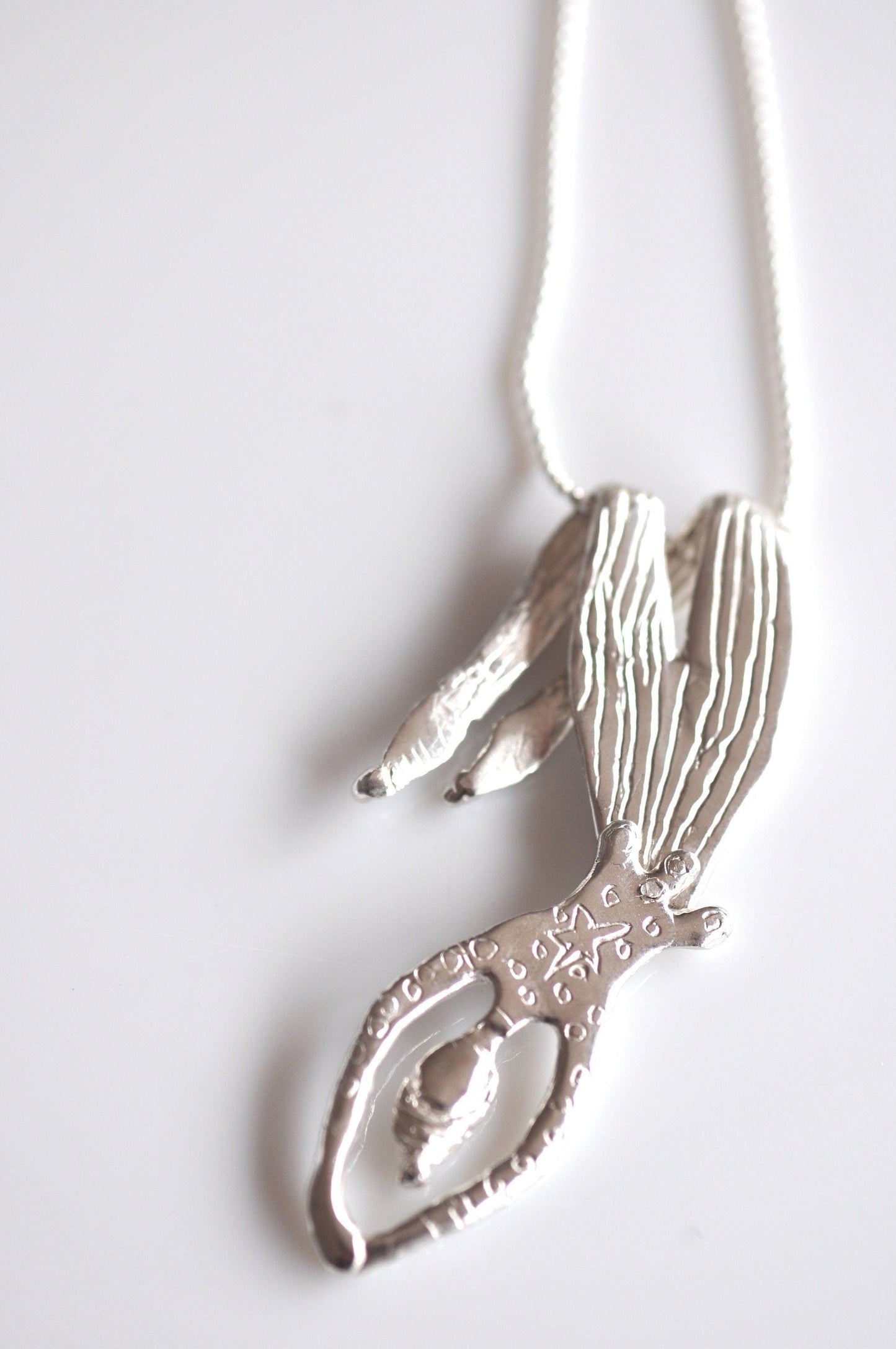 a silver necklace with a bird on it