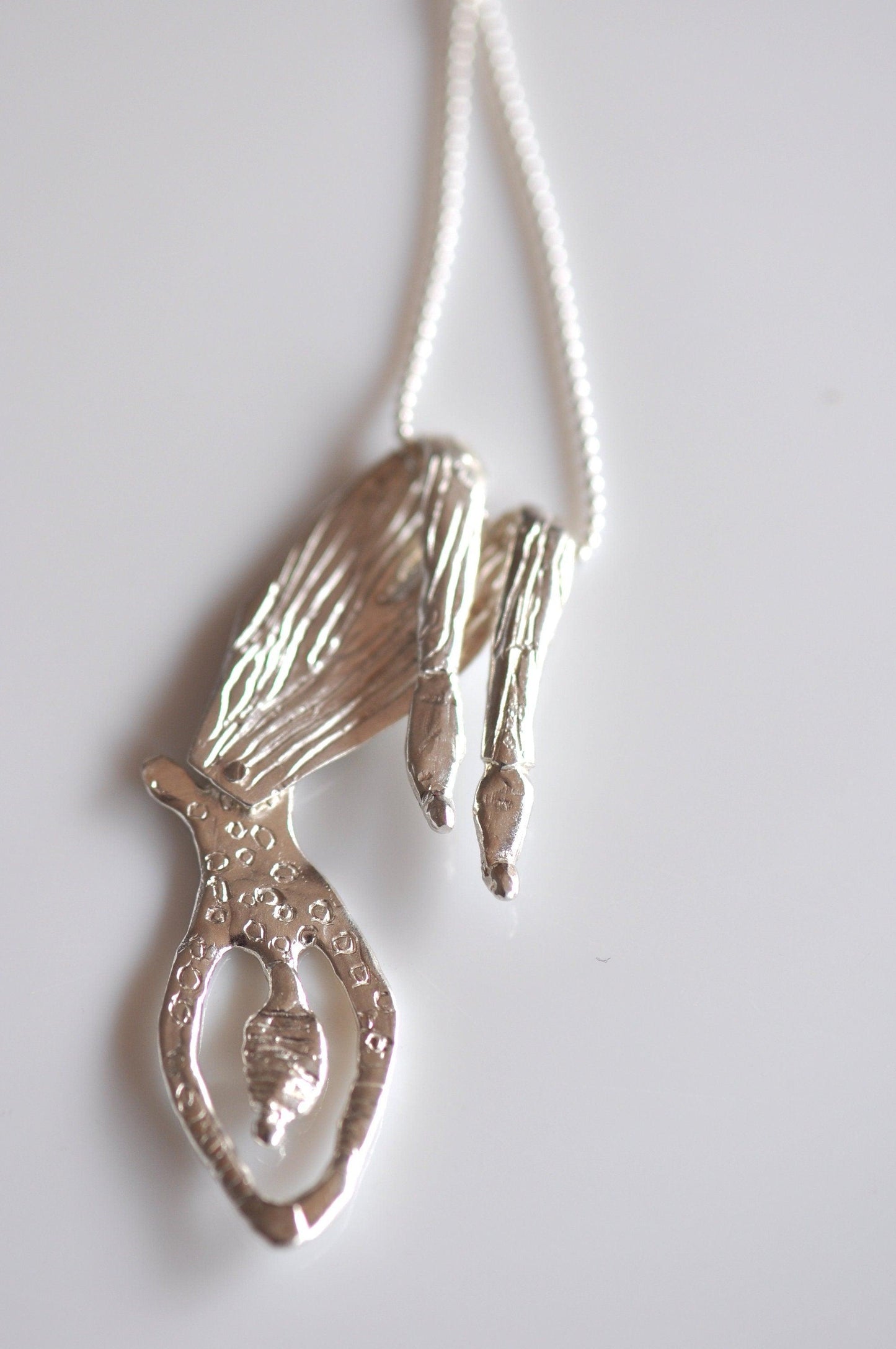 a silver necklace with a bird on it