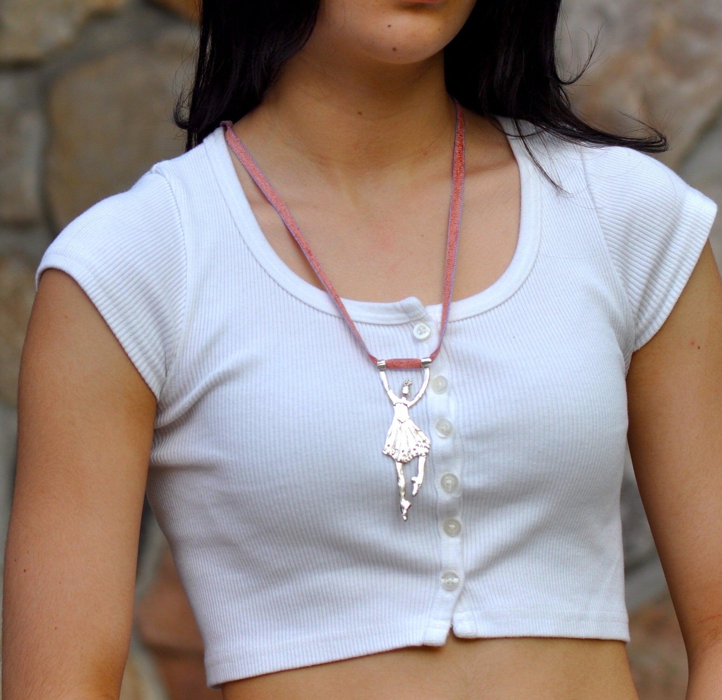 a woman wearing a white shirt and a pink necklace