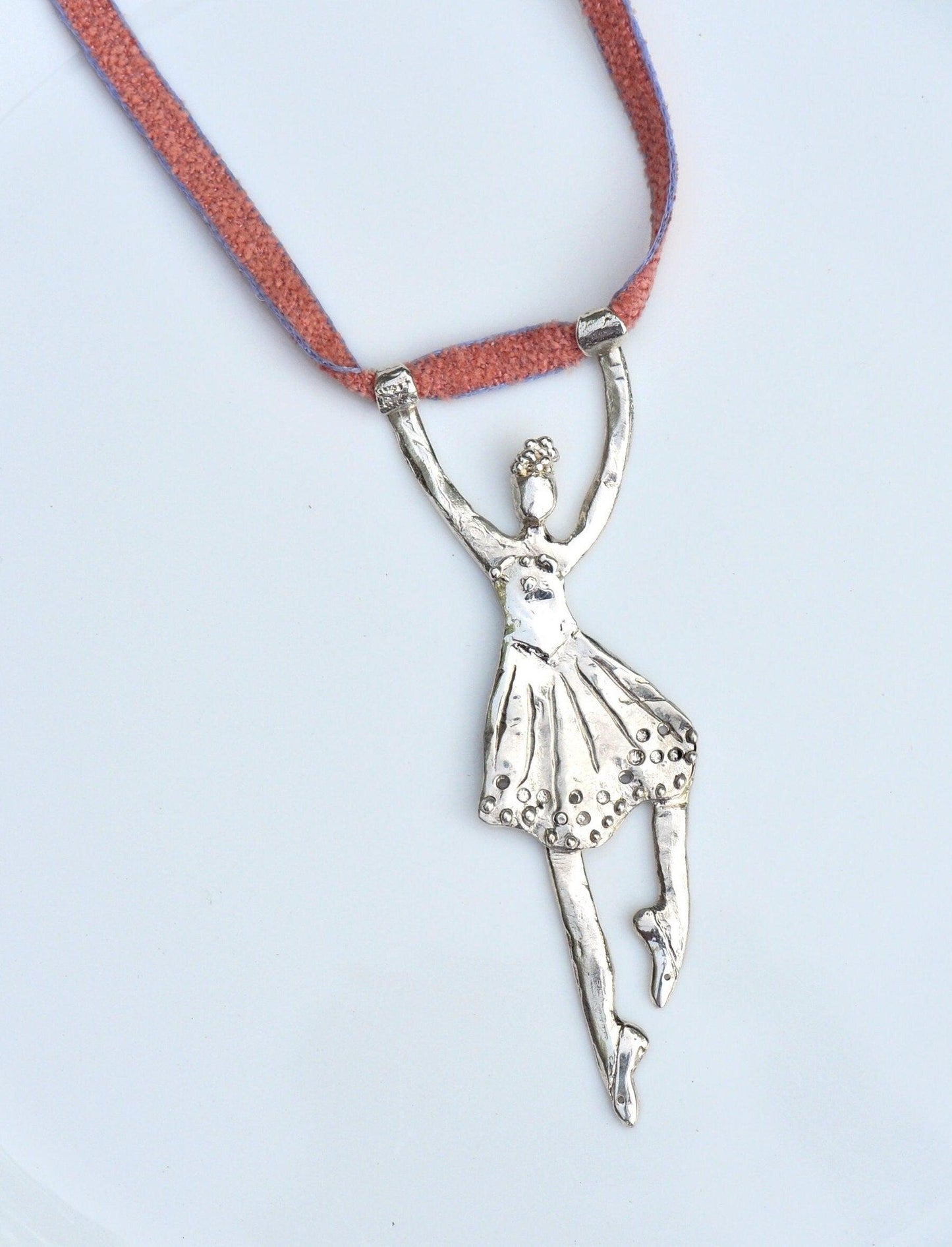 a silver ballerina pendant on a red cord