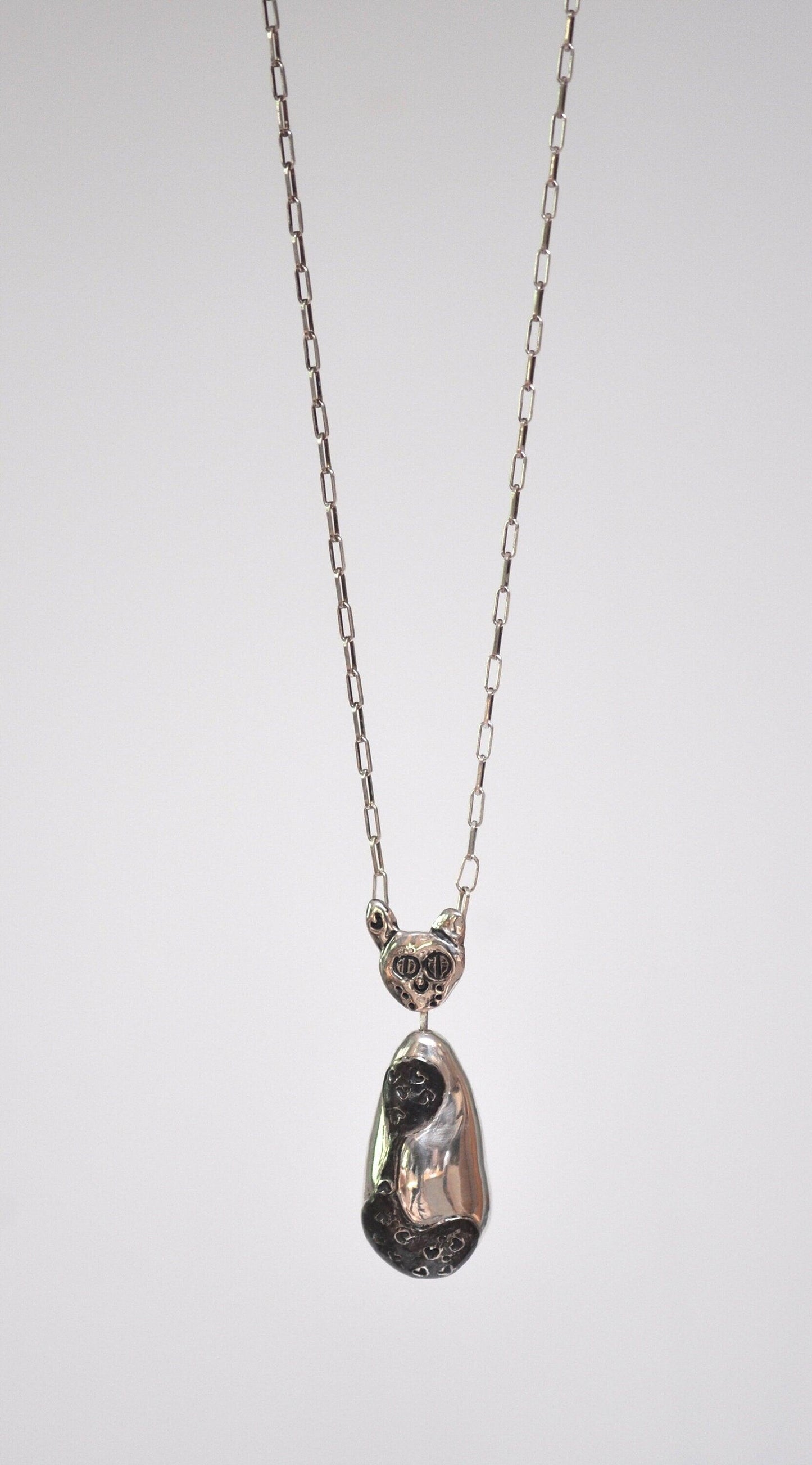 a necklace with a cat head hanging from a chain