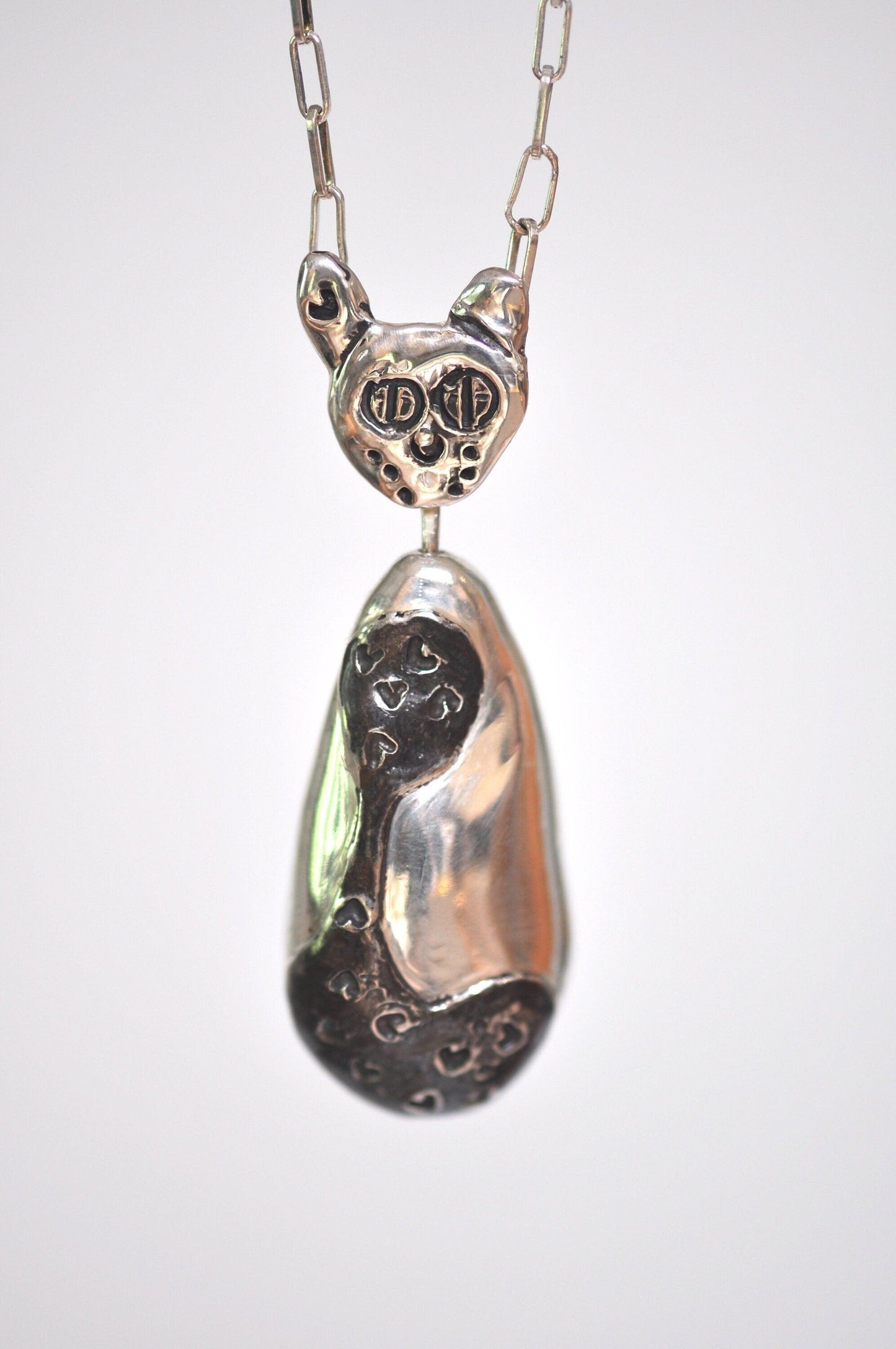 a silver necklace with a black cat on it