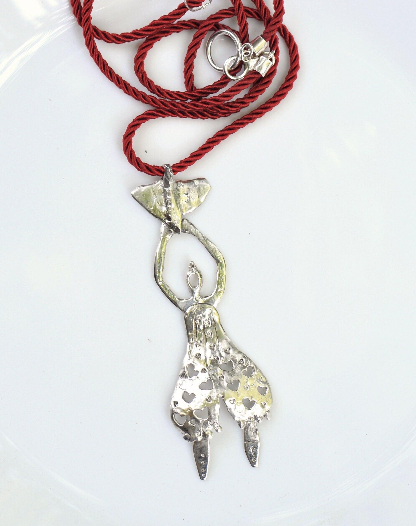 a red rope with a silver pendant on it