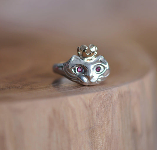 a silver ring with a cat's head on top of a wooden table