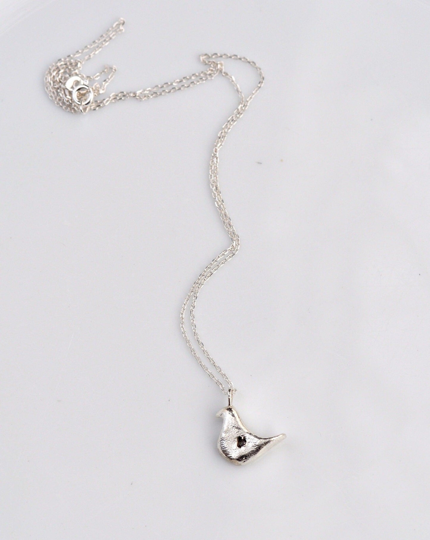 a silver necklace with a bird on it