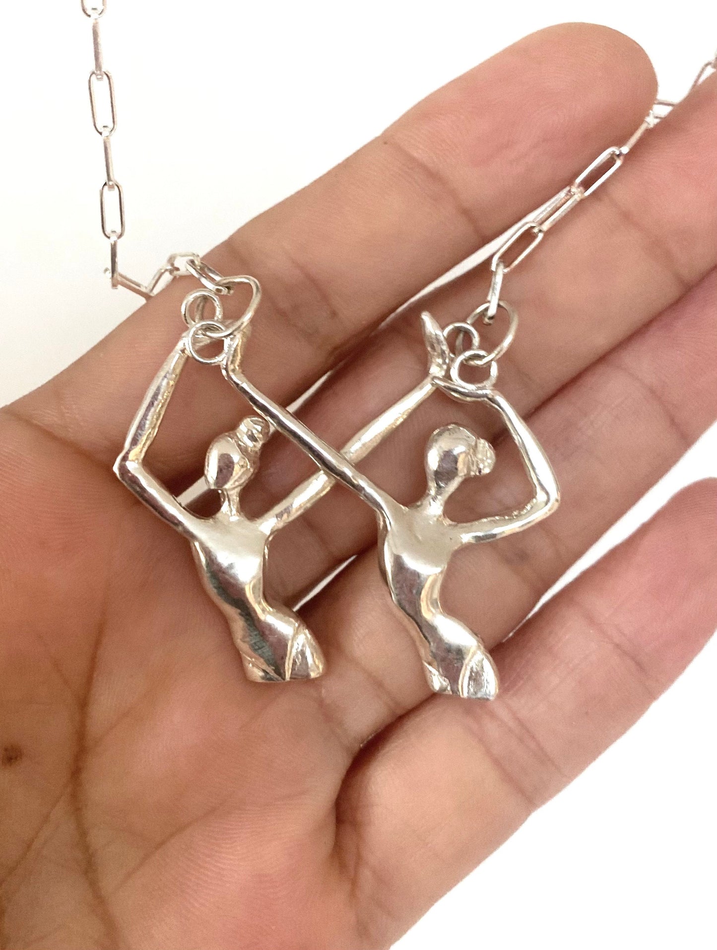 a person is holding a pair of silver earrings